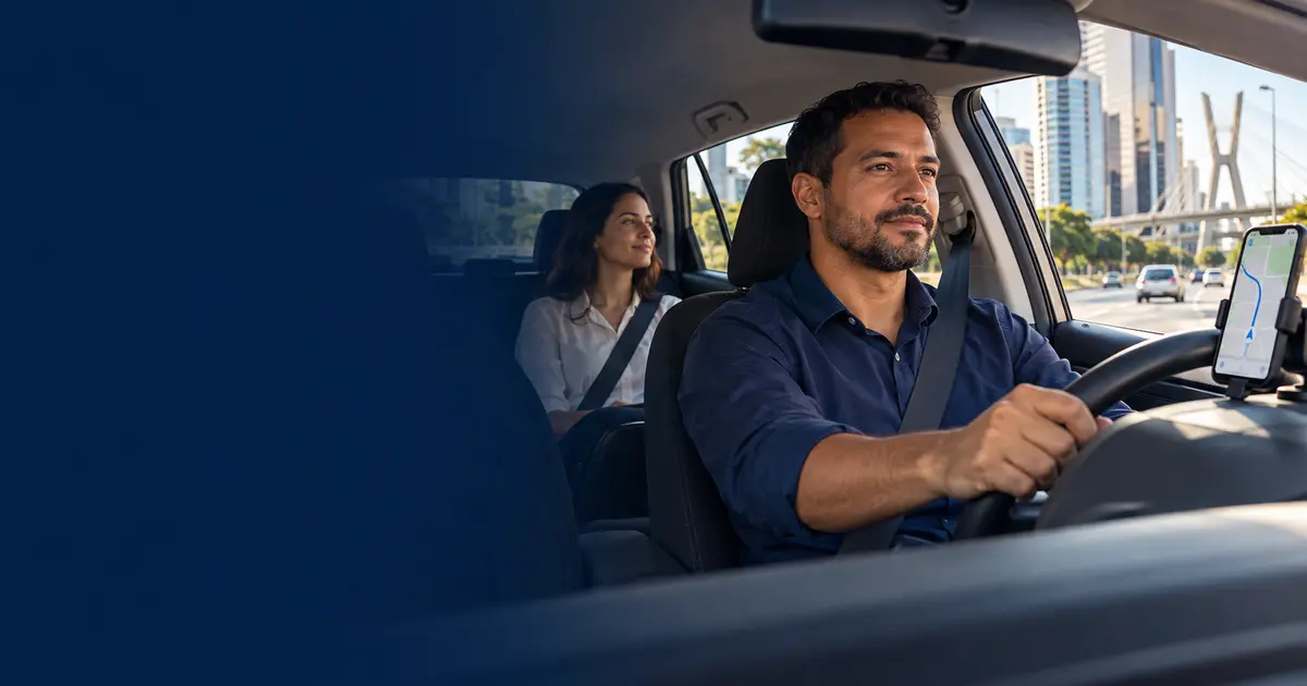 Motorista de aplicativo conduzindo um carro com passageira no banco traseiro e celular com mapa no painel